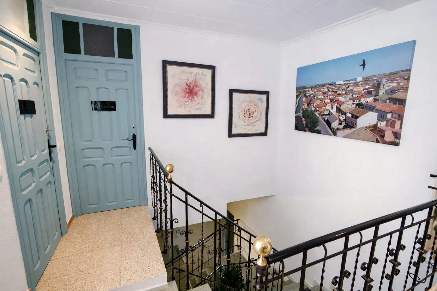 Pasillo de la planta superior con puertas azules y una fotografía de Fustiñana