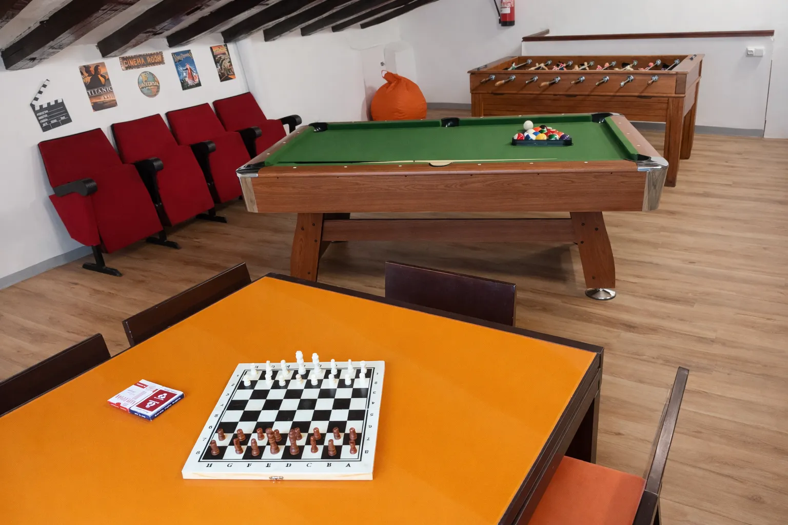 Sala de juegos con ajedrez, billar, futbolín y butacas de cine